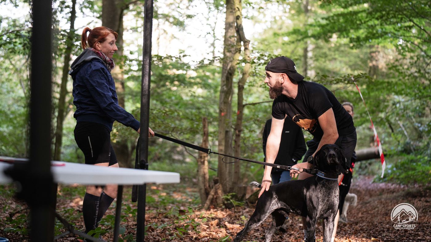 Départ d'une course de canicross, un coureur tient son chien en harnais